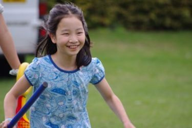 サマースクールの校庭を満面の笑みで元気に走る小学生の留学生