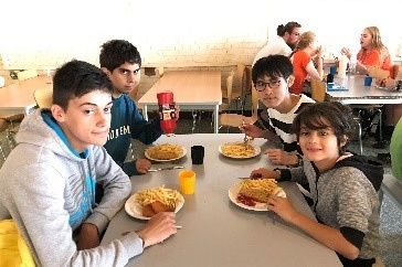サマーキャンプ場の食堂で学生たちが昼食をとっている様子